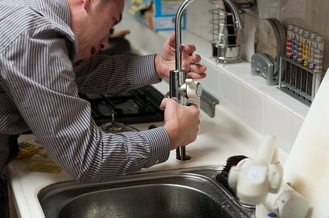 An image of a plumber working on a sink fixture.