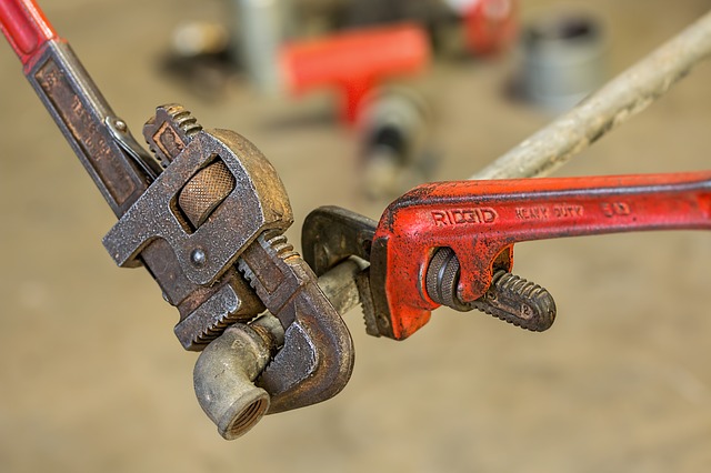 An image of two wrenches gripping a pipe.