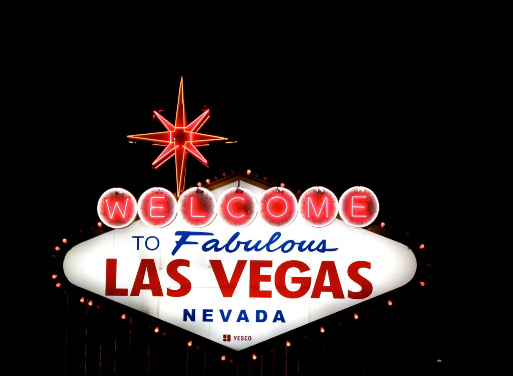 A close-up photograph of the famous “Welcome to Fabulous Las Vegas Nevada” sign lit up at night.