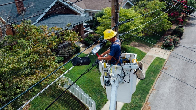 A man repairs electrical lines from a cherry picker.
