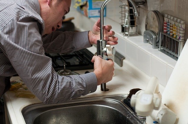 Male plumber fixing a sink faucet.