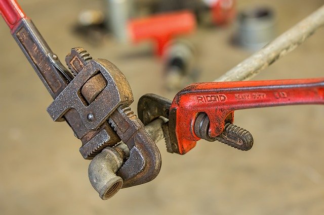 A photo of two pipe wrenches on a pipe.