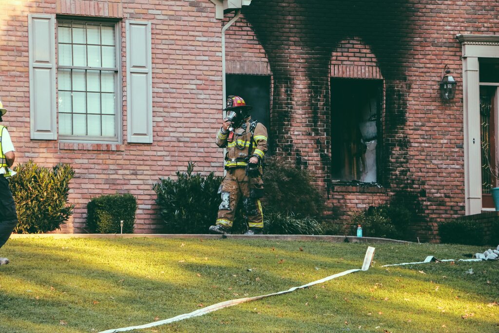 Firefighter walking out of a brick house that just burned