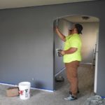 A contractor paints an archway inside a home.