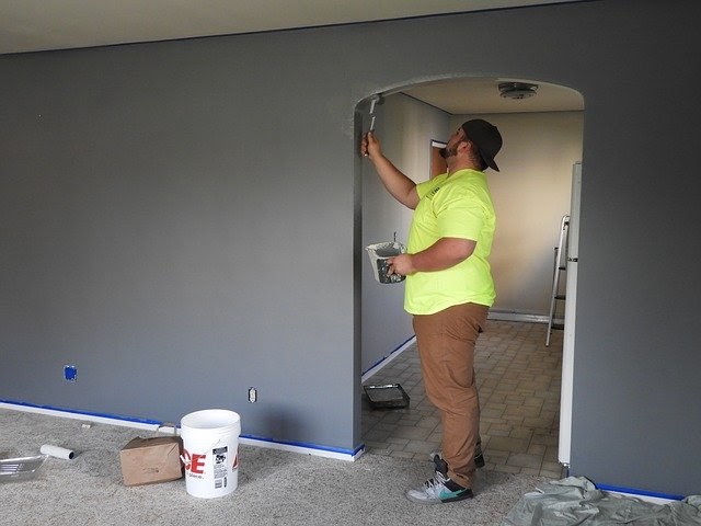 A contractor paints an archway inside a home.
