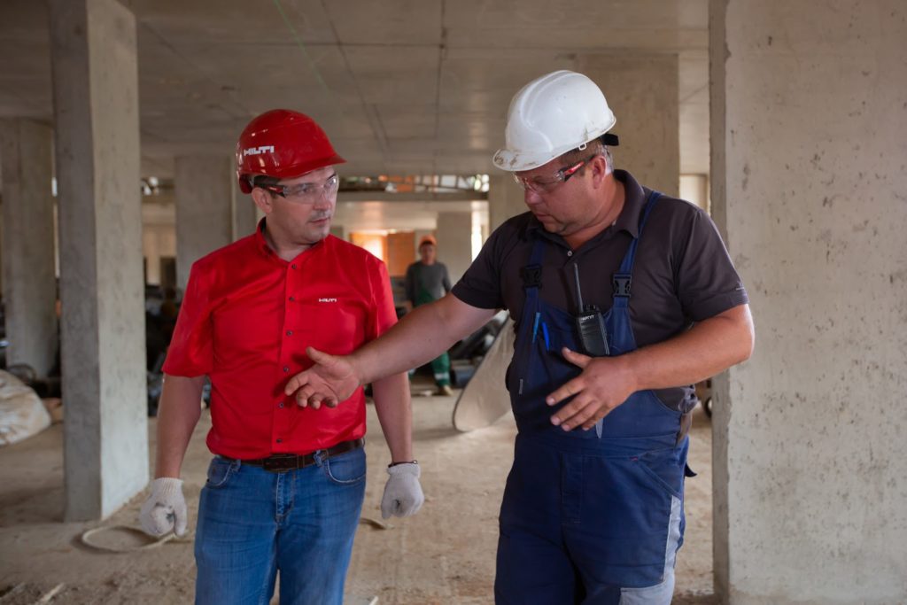 A construction manager and a contractor conversing on the job site. 