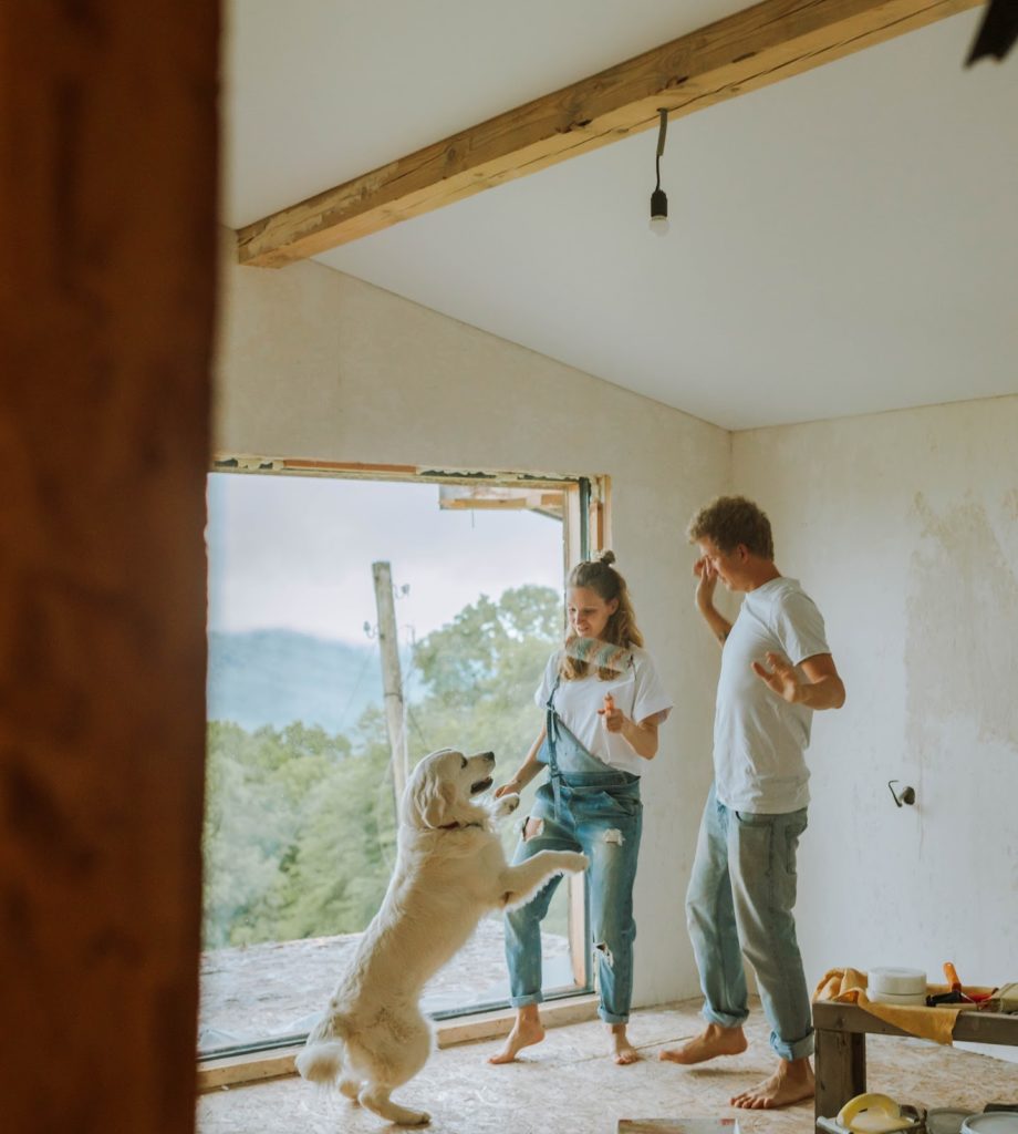 A couple remodels their home while playing with their dog.