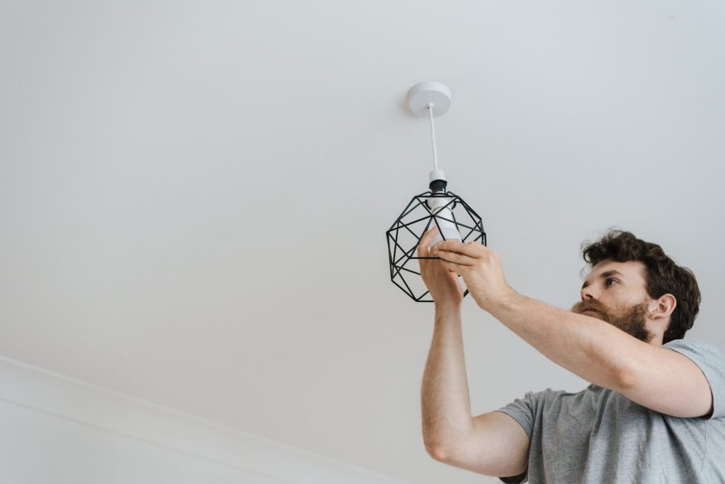 A person replacing the lightbulb in a room of their house.