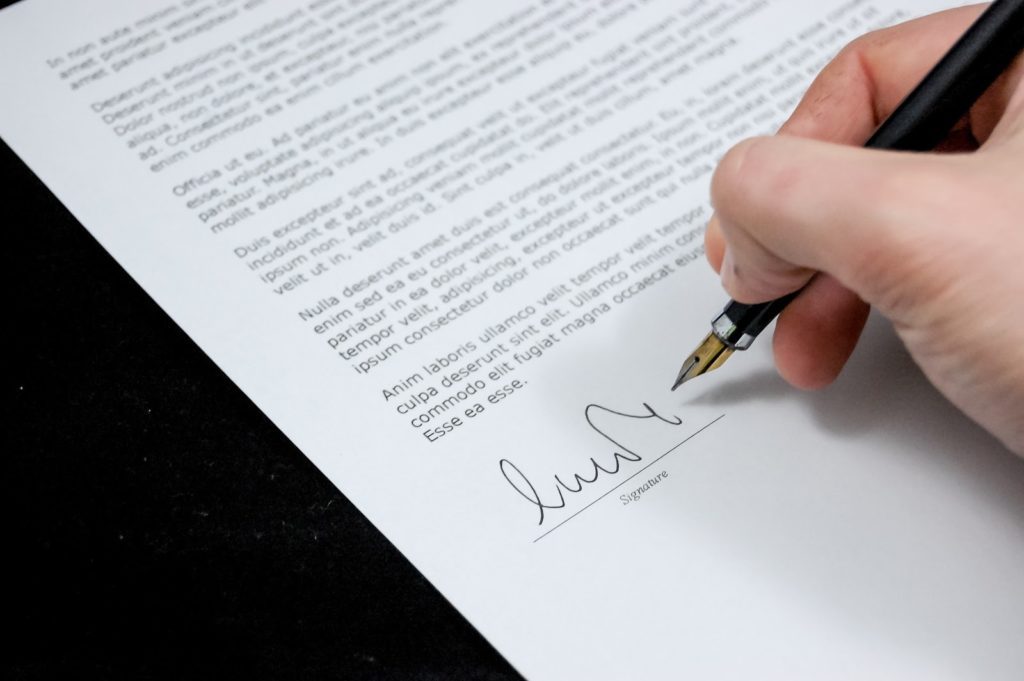 A closeup of a person signing a contract.