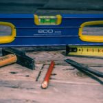 Level, hammer, tape measure, chisel, and pencil on work bench