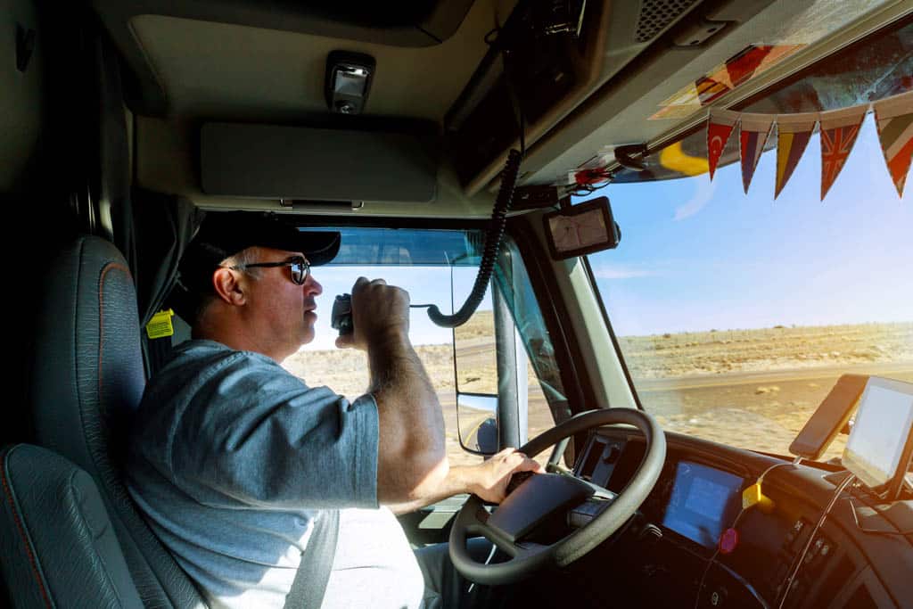 Male driver hands holding radio and steering wheel truck dashboard with driver